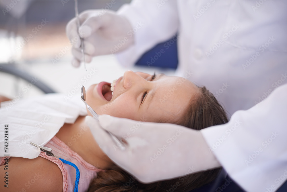 Girl, child and dentist with tools for healthcare, gum disease and oral hygiene with mouth inspection. Medical, orthodontics and consultation for teeth health, happiness and wellness with excavator Girl, child and dentist with tools for healthcare, gum disease and oral hygiene with mouth inspection. Medical, orthodontics and consultation for teeth health, happiness and wellness with excavator