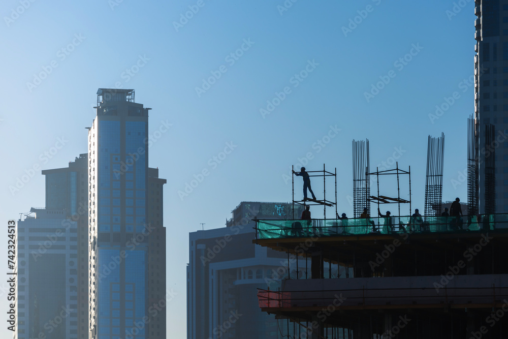 Skyscraper construction. Building under construction with workers at sunrise. Skyscraper construction. Building under construction with workers at sunrise.