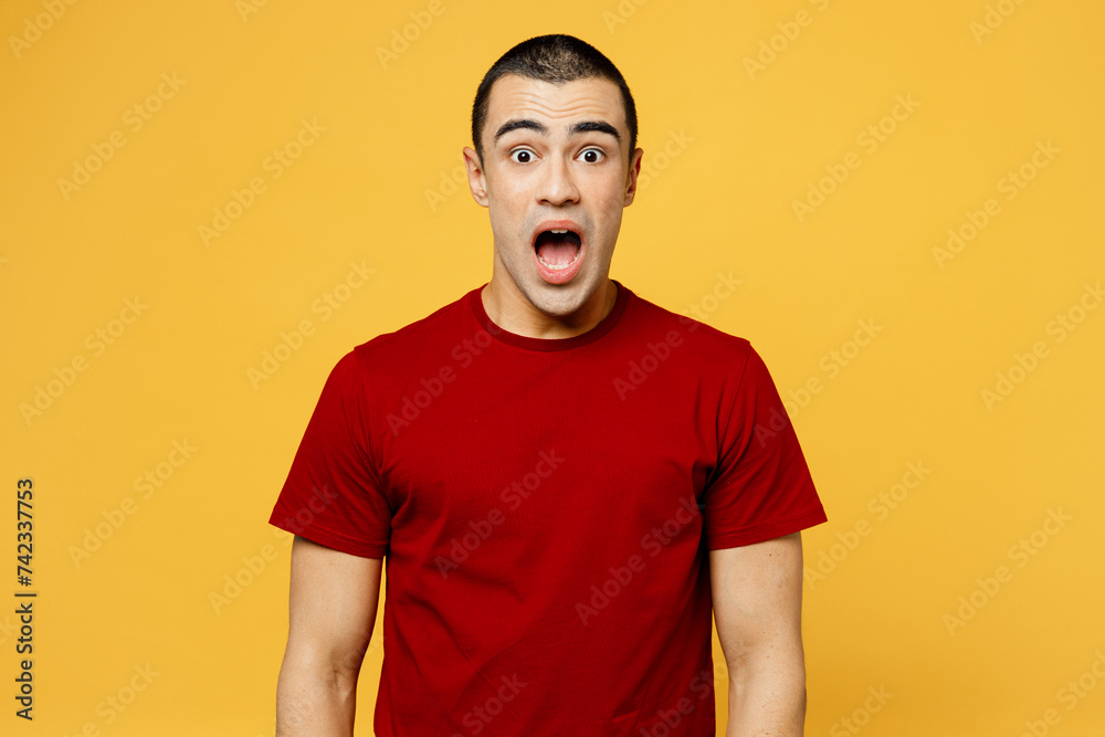 Young shocked mad astonished sad middle eastern man he wearing red t-shirt casual clothes look camera with opened mouth isolated on plain yellow orange background studio portrait. Lifestyle concept.