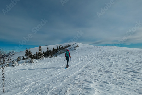 Woman with snowshoes in snow covered meadow on way to Hochanger, Muerzsteg Alps, Styria, Austria. Idyllic hiking trail along alpine snowy landscape. Winter wonderland in remote Austrian Alps