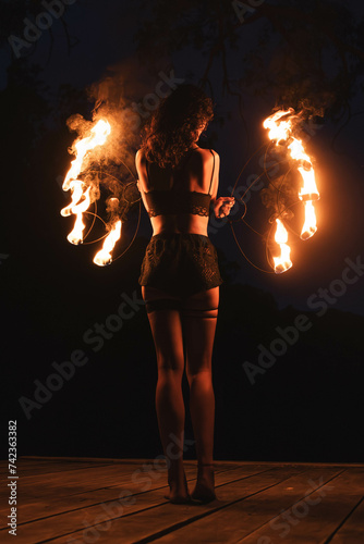 woman standing with fire torch against a sunset in the mountains