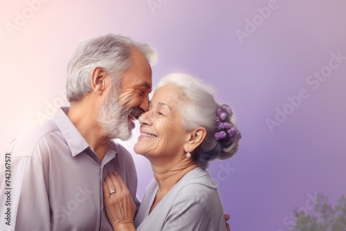
Elderly couple, both in their late 60s, Hispanic, enjoying a moment of closeness with their foreheads touching against a gentle lavender pastel background with copy space
