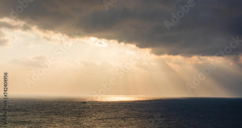 Majestic ocean sunrise scenery with sunlight shining through dark clouds