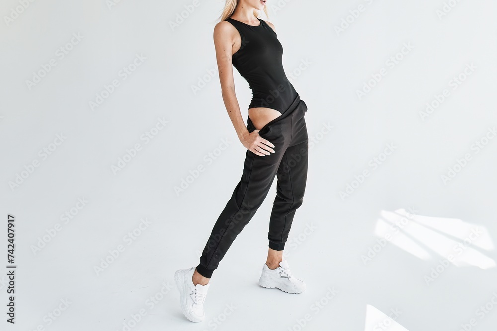 Well-shaped Athletic Young Woman wears Versatile Dark Trousers in Studio Well-shaped Athletic Young Woman wears Versatile Dark Trousers in Studio