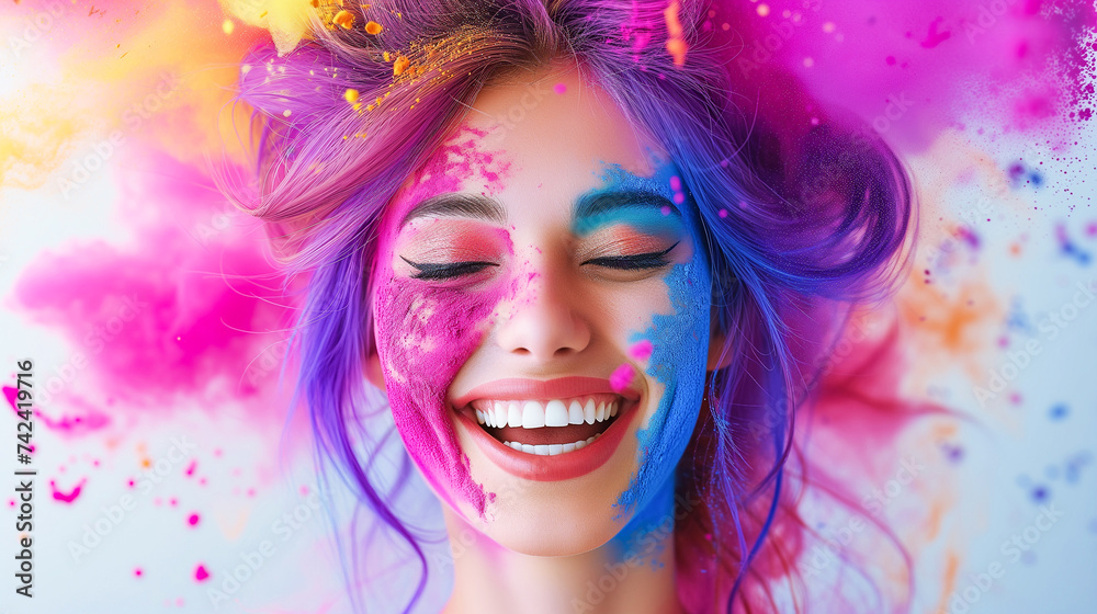 Portrait of a laughing young woman with a beautiful smile, covered with rainbow powder on a background with colorful powder, copy space. Celebrating the spring festival of Holi