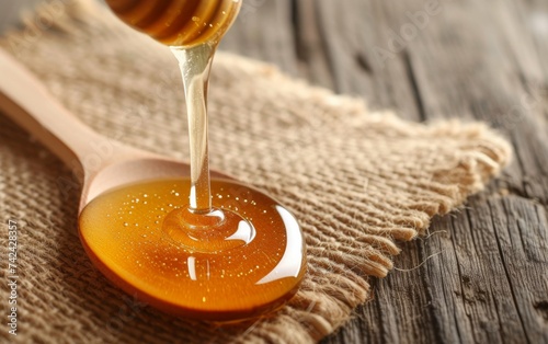 A spoon filled with honey is placed on top of a wooden table, showcasing the golden and sticky texture of the honey against the rustic backdrop