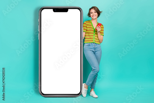 Full body photo of cheerful lady hold smart phone indicate finger empty space banner isolated on teal color background