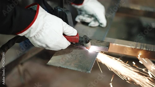 Heated metal plate surface being cut with oxy fuel torch in workshop, sparks and flame in the process of cutting, welder in protective gloves dividing steel on parts, metalwork and manufacturing photo