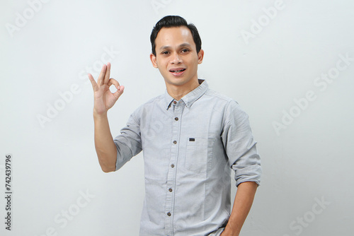 cheerful happy confident asian indonesian man with ok finger gesture on isolated background