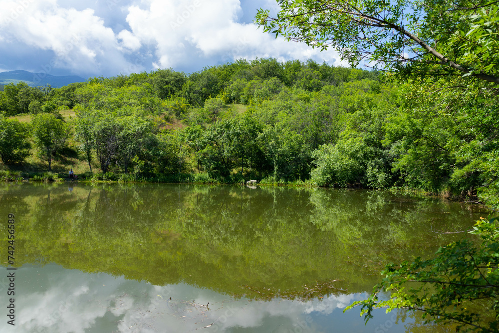 A small mountain lake in the Crimea against the background of mountains with clouds. Landscape.