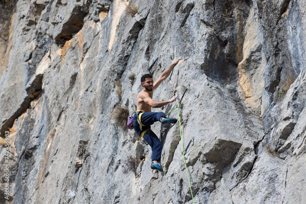 Shirtless man climbing in mountains, extreme nature sport