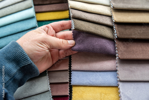 Male hand choosing perfect colorful fabric samples for new sofa and chairs in new home photo