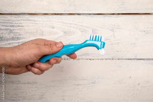 Denture toothbrush in hand. Effective cleaning of teeth and gums