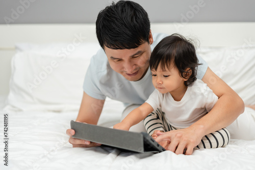 toddler baby with father using digital tablet pc on bed