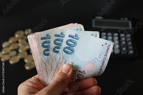 Fototapeta Naklejka Na Ścianę i Meble -  man counting Turkish money with his hand. Turkish lira banknotes. The paper currency of Turkey.Calculator in the background. For tax and hike news. raise, tax, minimum wage