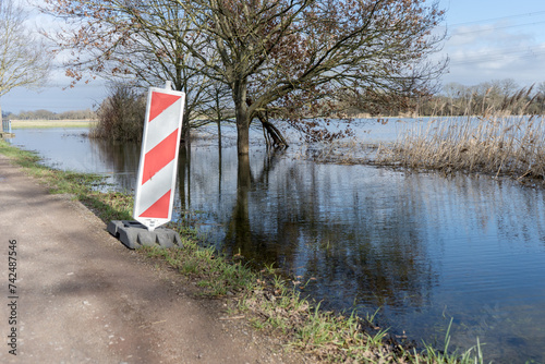 Road next to flooded meadows with warning bark