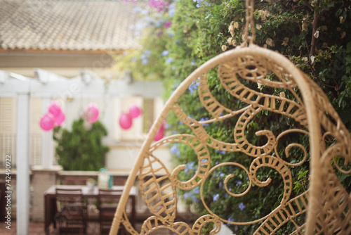 Close-up of a hanging chair in a garden with pink balloons hanging on a pergola in background photo