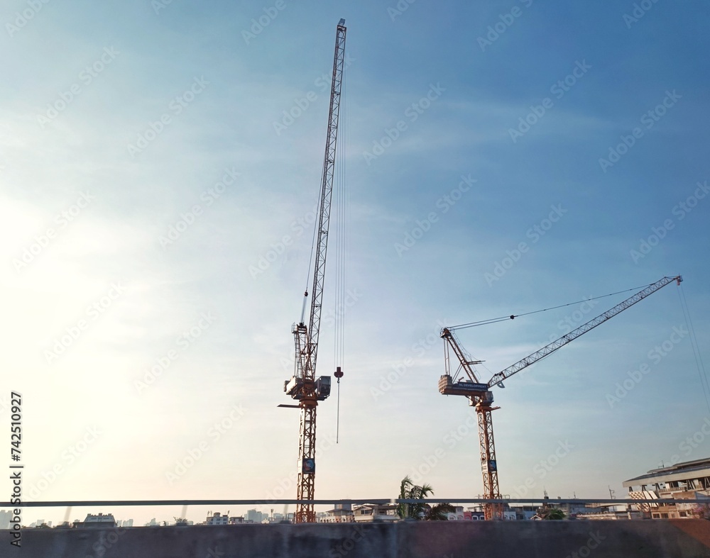 A view from a bridge of two cranes with a clear sky as a background A view from a bridge of two cranes with a clear sky as a background