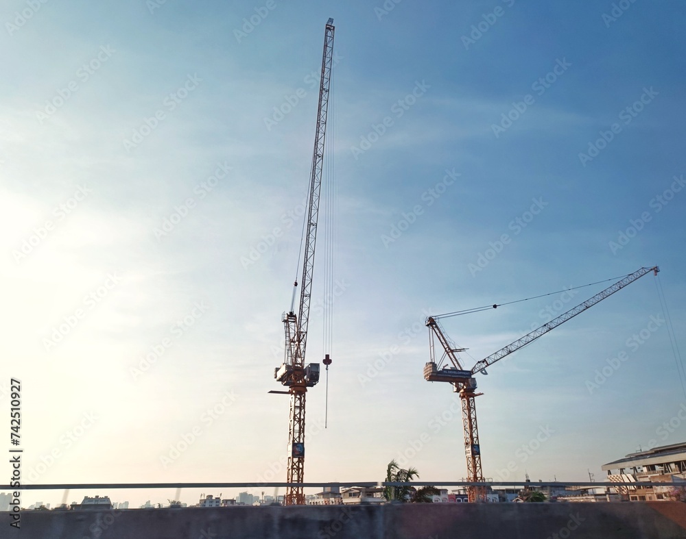 A view from a bridge of two cranes with a clear sky as a background