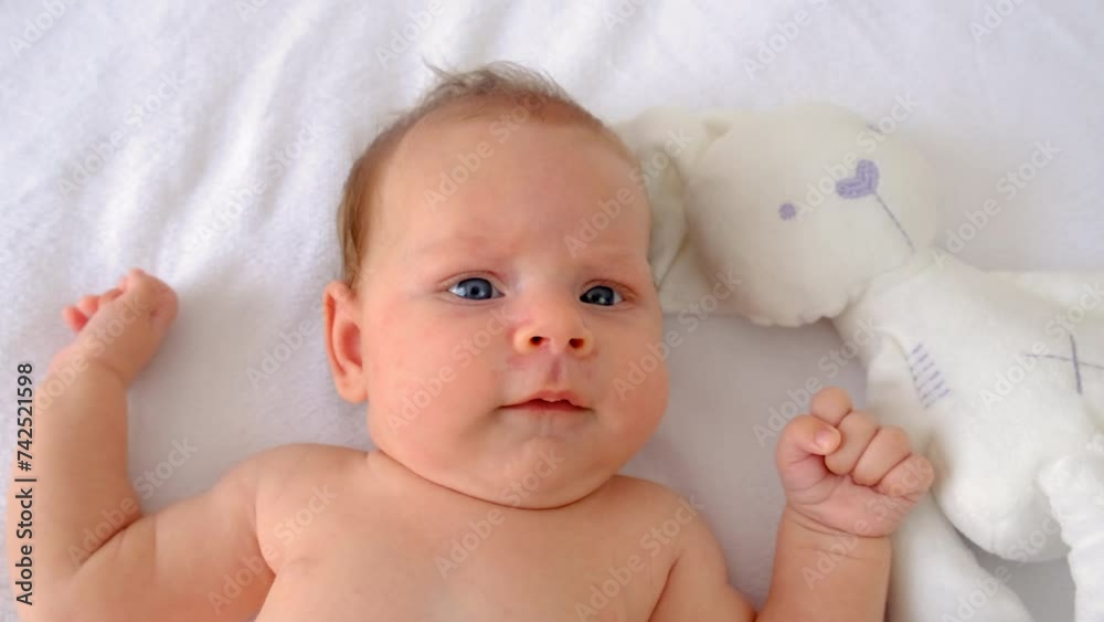 The baby is lying on the bed playing. Selective focus. The baby is lying on the bed playing. Selective focus.