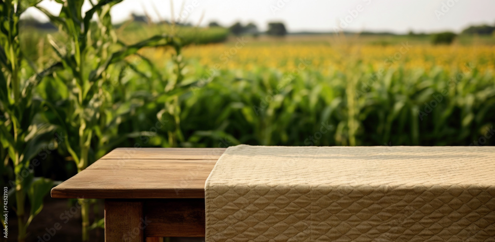Empty wooden table and tablecloth with corn field in the background. High quality photo