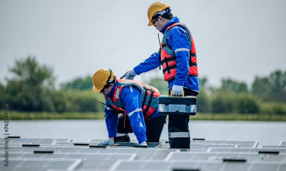 Obraz premium Engineers inspect the structural stability and alignment of floating solar panel arrays as QC work.