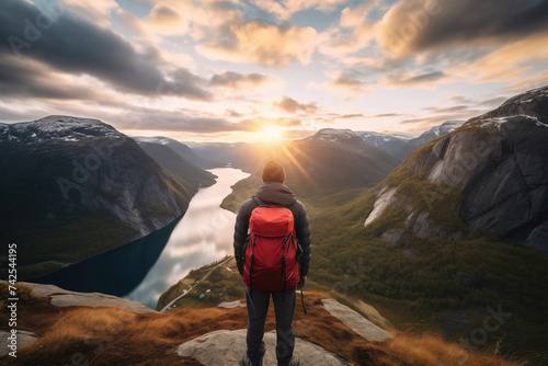 Back view of tourist standing on top of a rock and enjoying fascinating view with mountains and lakes around. Concept of adventure in Scandinavian countries