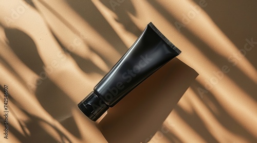 A bird's eye view of a black tube of face cream under sunlight. The container...