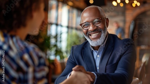 A middle-aged businessman smiles as he shakes hands with his partner