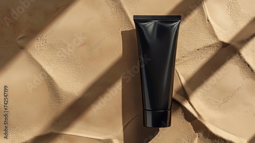 A bird's eye view of a black tube of face cream under sunlight. The container...