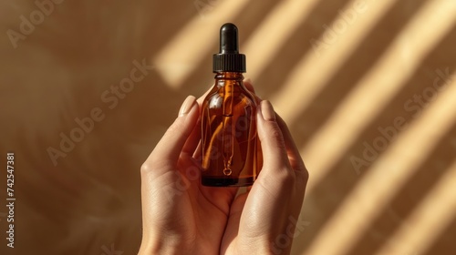 Mockup featuring a glass bottle with a dropper lid held in female hands