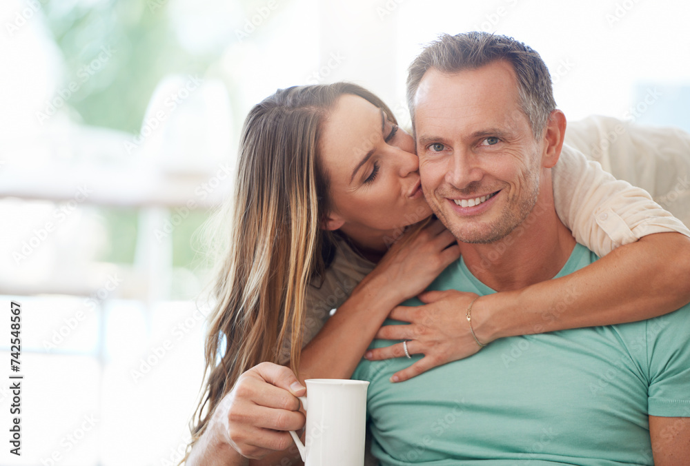 Happy couple, kiss and portrait with coffee in home, romantic and husband proud of wife love in marriage. Man, woman or excited face for touch with warm drink or feelings by sofa in modern apartment Happy couple, kiss and portrait with coffee in home, romantic and husband proud of wife love in marriage. Man, woman or excited face for touch with warm drink or feelings by sofa in modern apartment