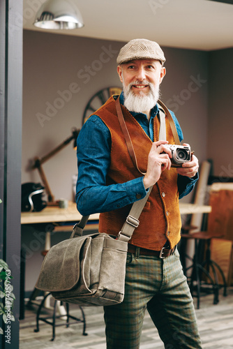 Portrait d'un photographe homme barbu chic hipster élégant et stylé qui porte un appareil photo vintage argentique dans un atelier créatif