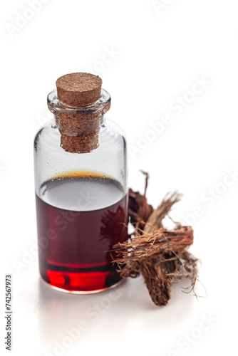 Dry organic Jatamansi (Nardostachys jatamansi) roots, along with its essential oil. Isolated on a white background. photo