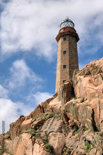 lighthouse on a rock against a background of blue sky with clouds © sergiy1975