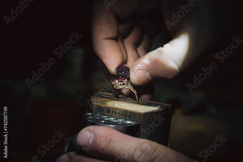master of jewelry manually inserts gems into the frame of future jewelry. Working desk for craft jewelry making with professional tools. Sapphire diamond ring on the jeweler's desktop