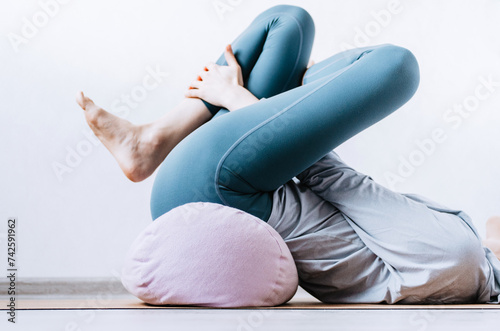 Bild auf Leinwand Woman doing yin yoga passive hip stretch exercises on bolster