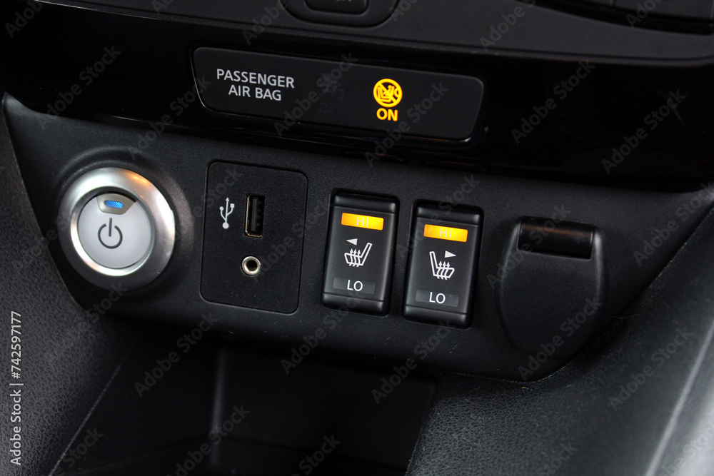 Electric car dashboard. Start stop button electric car and seat heating buttons. Double seat heating switch in a car. Car interior detail. Engine start button.