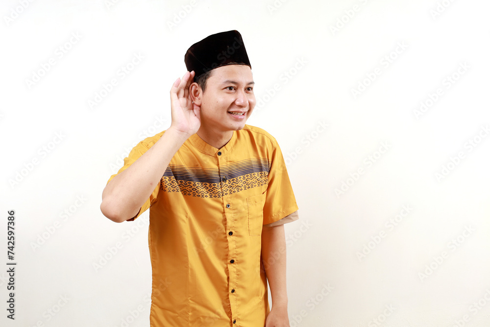 Asian muslim man wearing a typical arab clothes trying to listening a gossip isolated on white background Asian muslim man wearing a typical arab clothes trying to listening a gossip isolated on white background
