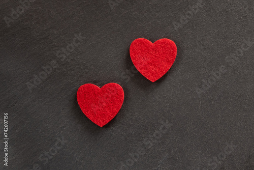 Red fabric heart shape over black nature background.