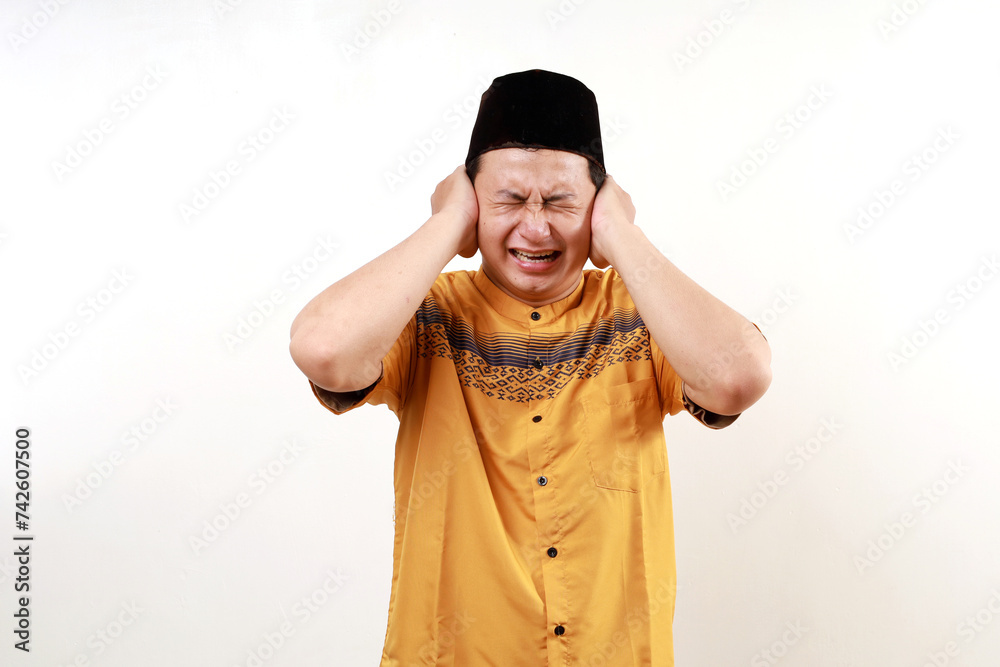 Young asian man covering ears with hands trying not to hear too loud sound. Young asian man covering ears with hands trying not to hear too loud sound.
