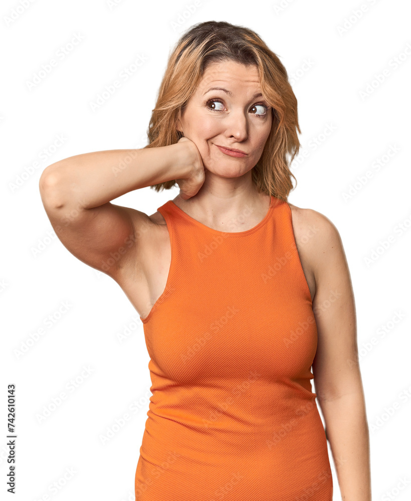 Blonde middle-aged Caucasian woman in studio touching back of head, thinking and making a choice. Blonde middle-aged Caucasian woman in studio touching back of head, thinking and making a choice.