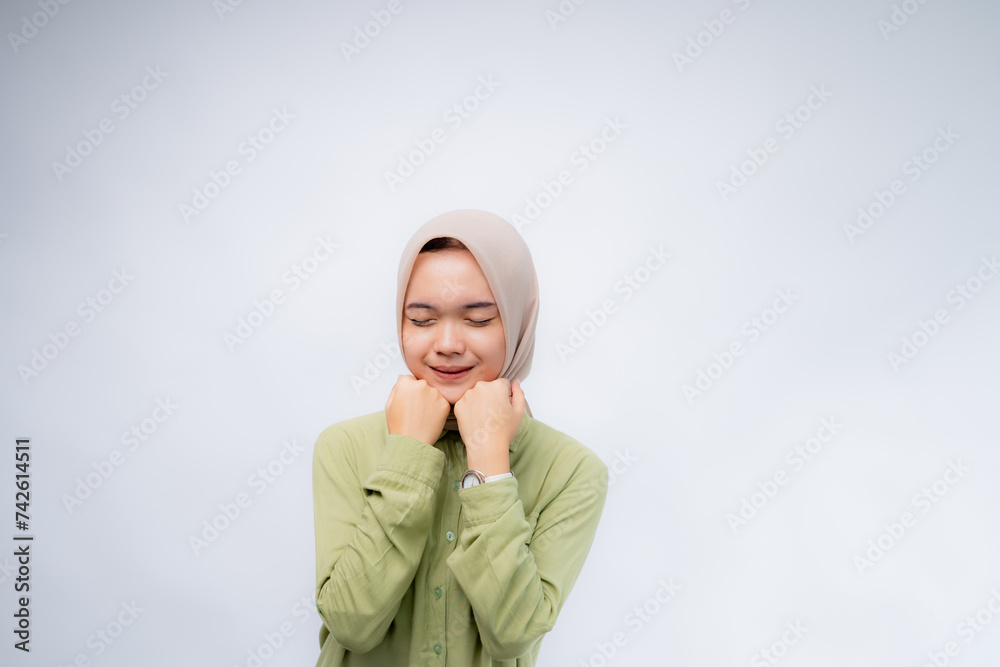 Excited. Portrait of young asian woman wearing hijab clenched his fist on his forehead at Copy Space Advertising Your Text, Standing Isolated Over white Studio Background Excited. Portrait of young asian woman wearing hijab clenched his fist on his forehead at Copy Space Advertising Your Text, Standing Isolated Over white Studio Background