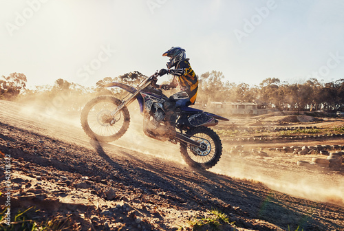 Hill, race and man on dirt bike in desert with adventure, adrenaline and speed in competition, Extreme sport, dust and athlete on off road motorcycle for challenge, power or danger on action course