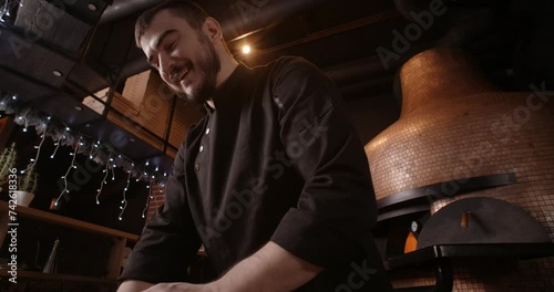 Pizza chef smiles and tosses the dough in the restaurant photo