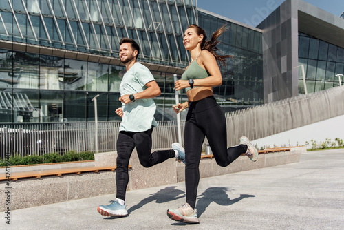 Energetic couple running in an urban environment, showcasing fitness and vitality.