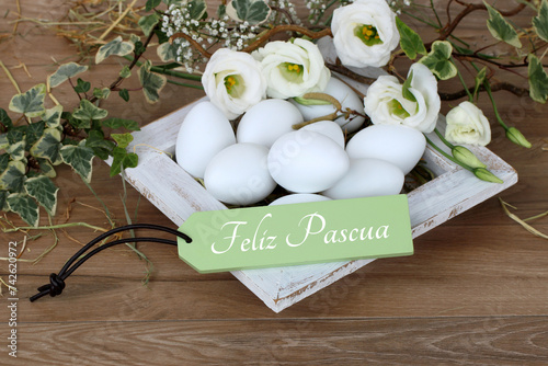 Tarjeta de felicitación Felices Pascuas: canasta de Pascua con huevos y saludo de Pascua en un cartel. photo