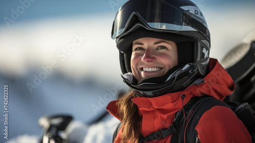A beaming woman in a helmet and red ski jacket embodies the thrill of snowmobiling, set against a blurred snowy backdrop. © Sascha