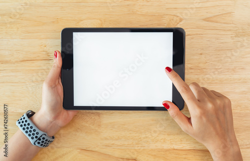 Hands holding digital tablet with mockup of blank screen on desk in office room.