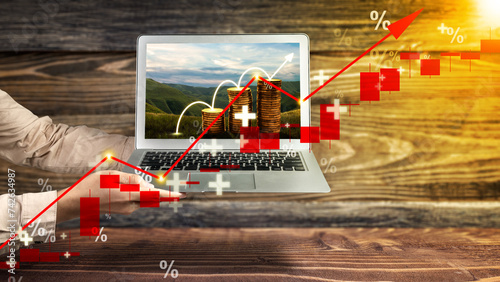 Business hand showing laptop screen with a view of stair stack of the golden coin with rising inflation graph arrow